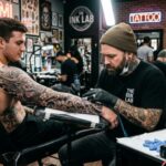 Tattoo artist creating a detailed black and gray sleeve at a Miami tattoo shop